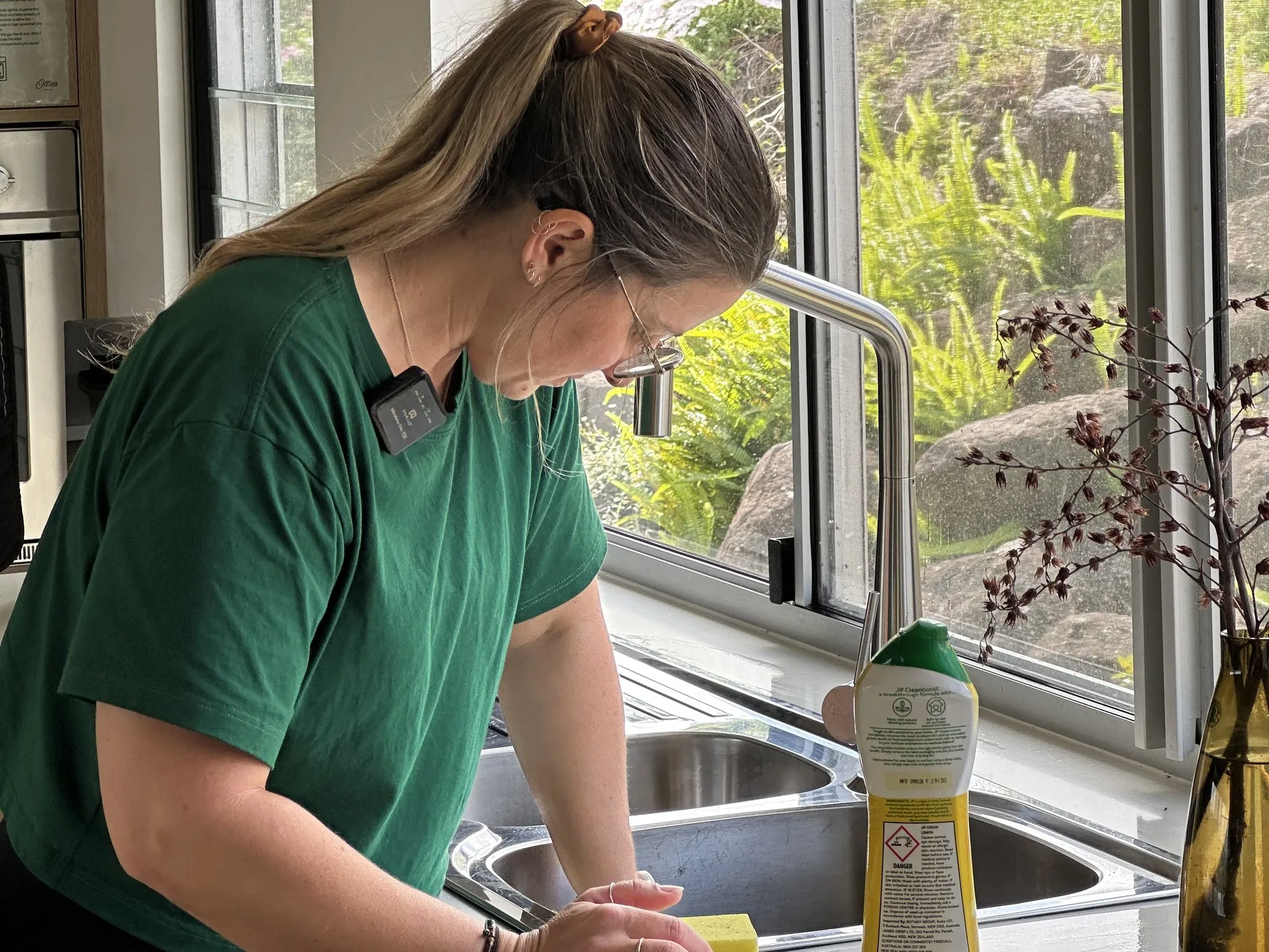 A TLB cleaner wiping down the kitchen bench beside the sink