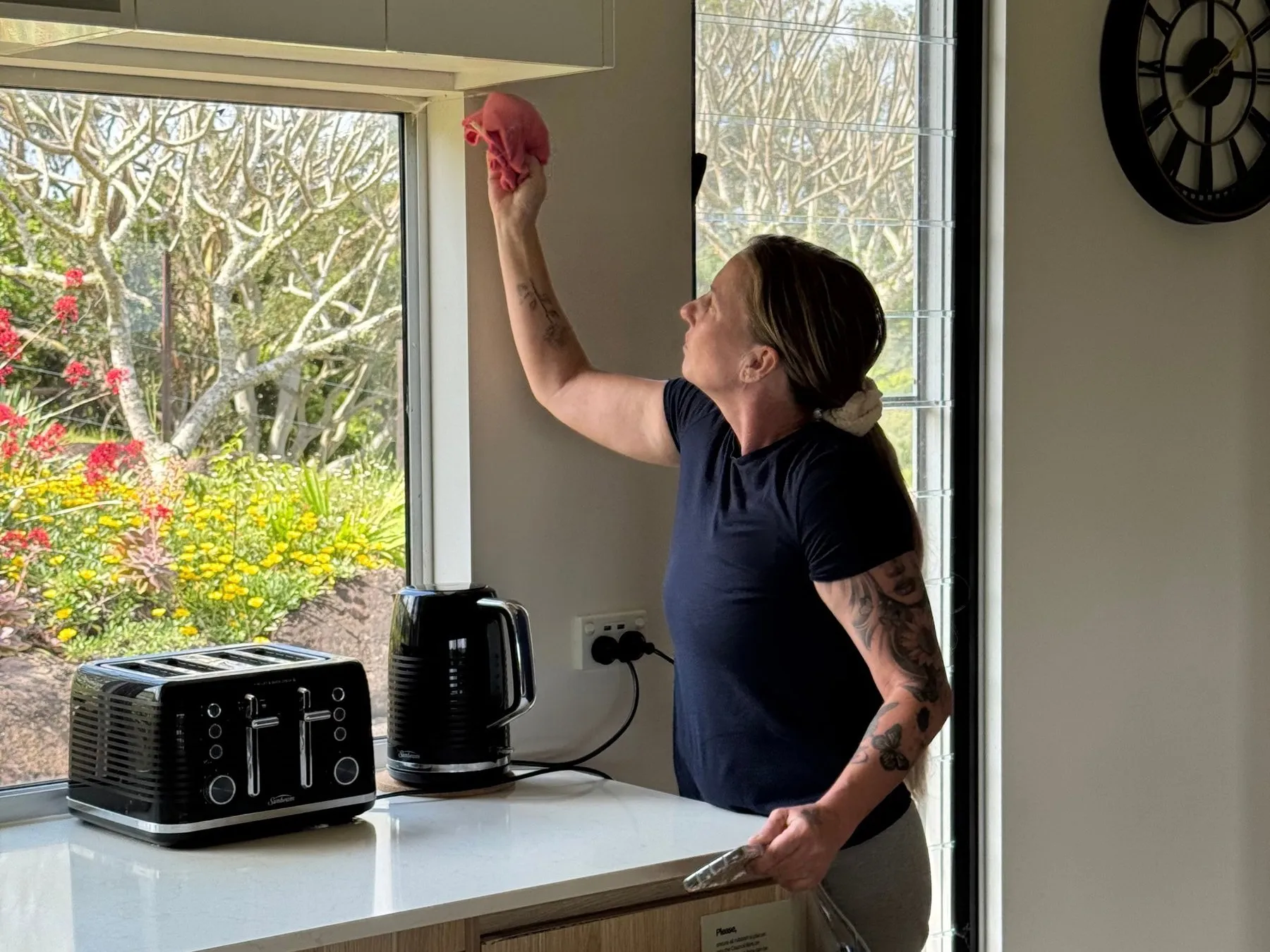 Cleaner wiping down a kitchen window frame