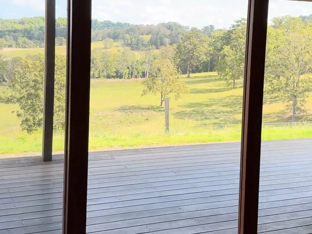 A cleared room with glass doors open onto the deck and paddock
