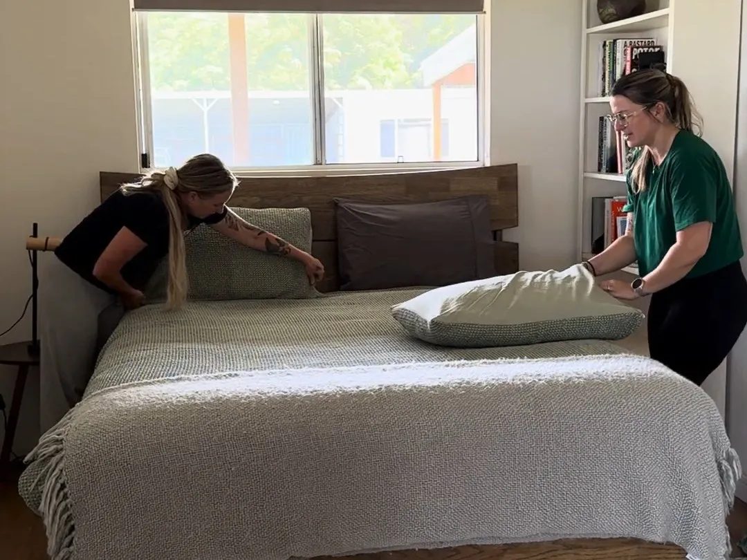 Two TLB cleaners making up a bed during a regular house clean