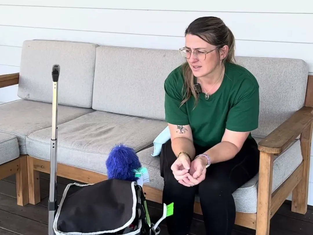 A TLB cleaner sitting on a verandah lounge beside her cleaning caddy